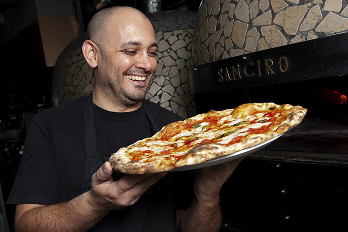 Lo chef Ciro Di Maio sorride mentre mostra la 'pizza della felicità' appena sfornata presso la Pizzeria San Ciro